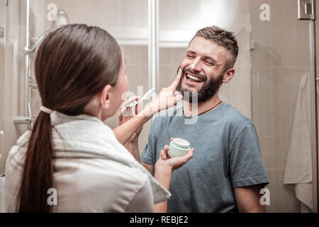 Schöne angenehme Frau, die Creme auf Ihre Freunde Gesicht Stockfoto