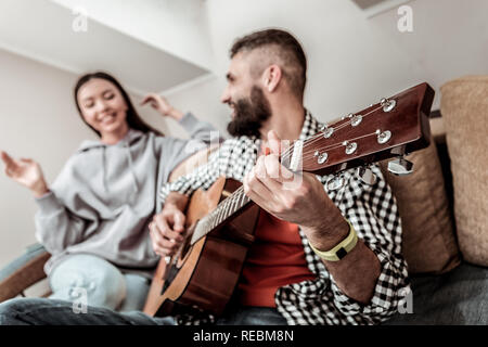 Netter junger Mann mit einer Gitarre erfreut Stockfoto