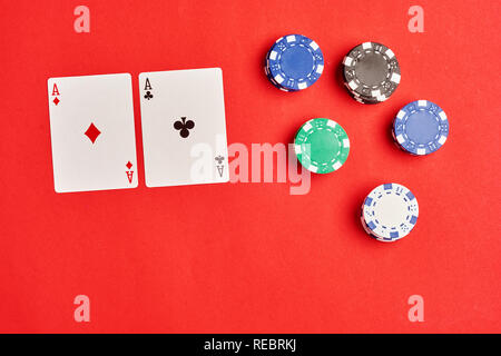 Flach oder der Ansicht von oben. Stapel Chips und zwei Asse auf der Tabelle auf den roten Hintergrund - Poker spiel Konzept. Stockfoto