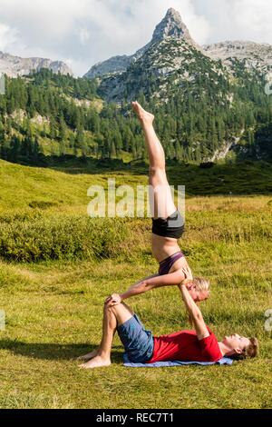 Junge Frau und ein junger Mann tun acro Yoga, Berglandschaft, Nationalpark Berchtesgaden, Berchtesgadener Land, Oberbayern Stockfoto