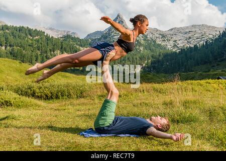 Junge Frau und ein junger Mann tun acro Yoga, Berglandschaft, Nationalpark Berchtesgaden, Berchtesgadener Land, Oberbayern Stockfoto