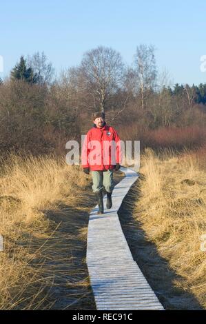 Hautes Fagnes finden im Winter, Mann zu Fuß auf einem gefrorenen Boardwalk, Eupen, Provinz Lüttich, Belgien Stockfoto