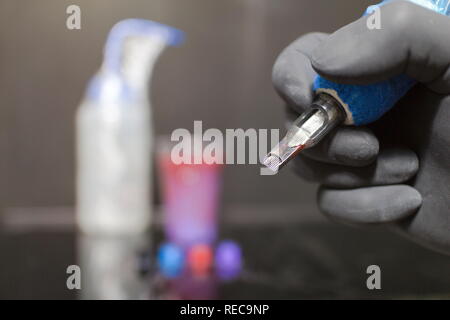 Tattoo artist Holding ein Tattoo Maschine zur Hand und Tattoo Tinte in die Kappen auf die Tabelle in Tattoo Studio. Stockfoto