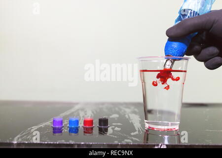 Tattoo artist Holding ein Tattoo Maschine zur Hand und Tattoo Tinte in die Kappen auf die Tabelle in Tattoo Studio. Stockfoto
