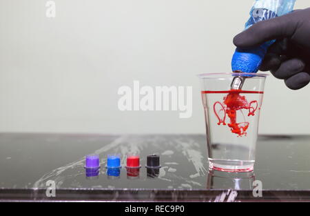Tattoo artist Holding ein Tattoo Maschine zur Hand und Tattoo Tinte in die Kappen auf die Tabelle in Tattoo Studio. Stockfoto