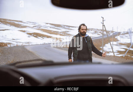 Reisender auf der Landstraße, die versuchen, ein Auto für Hilfe zu stoppen Stockfoto