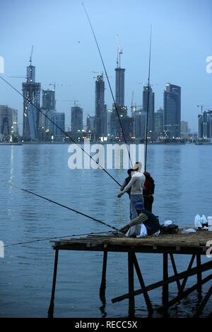 Fischer am Abend auf einem Steg auf Doha Bay, neu errichtete Gebäude, Hochhaus liegt am nördlichen Ufer des Stockfoto