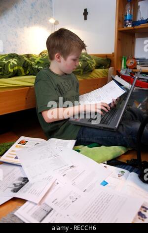 Junge, 11, Arbeiten mit seinem Computer zu Hause in seinem Schlafzimmer tun Schule Hausaufgaben Stockfoto