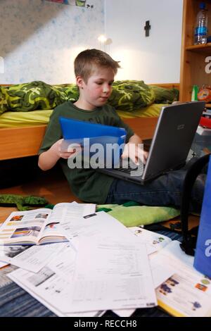 Junge, 11, Arbeiten mit seinem Computer zu Hause in seinem Schlafzimmer tun Schule Hausaufgaben Stockfoto