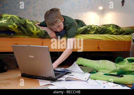 Junge, 11 Jahre alt, arbeiten mit seinem Computer zu Hause in seinem Zimmer, Hausaufgaben für die Schule