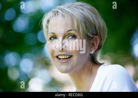 Porträt einer Frau, Anfang 40, im Garten, mit Blick auf die Kamera oder Lächeln Stockfoto