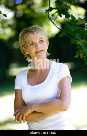 Porträt einer Frau, Anfang 40, im Garten, mit Blick auf die Kamera oder Lächeln Stockfoto