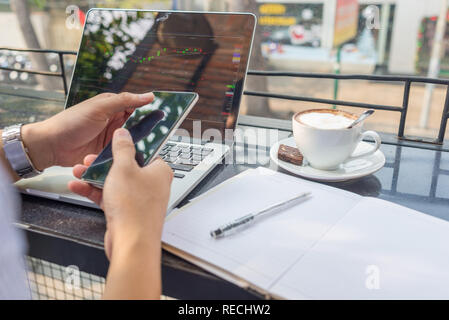 Asiatische Investor gerade die Änderung der Börse auf Laptop und Smartphone Stockfoto