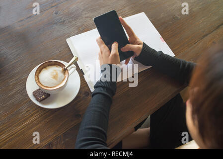 Junge Frau Sms auf Smartphone mit beiden Händen Stockfoto