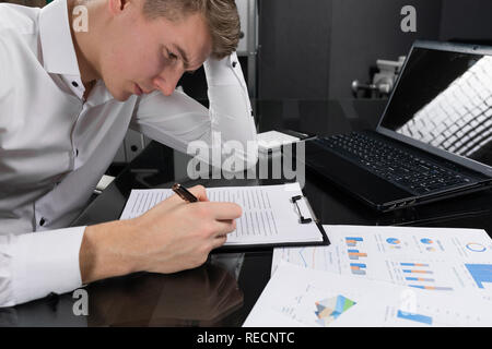 Junger Mann zeichen Versicherung im hellen Büro Stockfoto