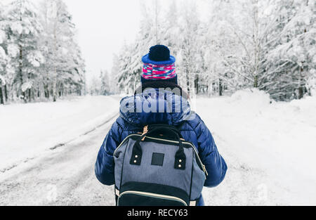 Reisen Lifestyle. Junge Frau mit Rucksack im Winter auf verschneiten Straßen in Schweden Stockfoto