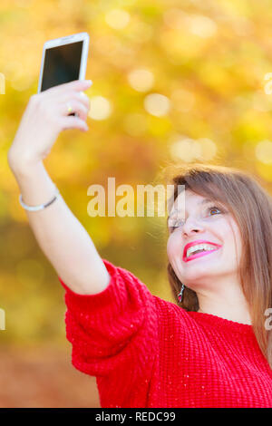 Technologie- und Spaß-Konzept. Angenehm attraktives Mädchen spielen mit Handy. Fröhliche wunderschöne Frau lächelnd unter selfie Foto in der Saison Herbst Stockfoto