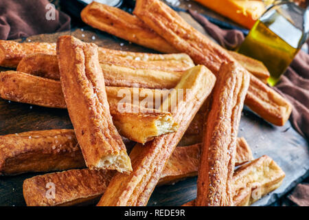 Close-up von Käse Strohhalme, kitschigen Brot klebt auf einem Holzbrett, Makro Stockfoto