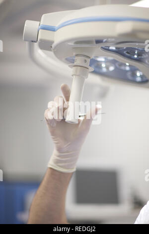 Ein Arzt mit einem zahnmedizinischen Sonde in seiner Hand legt den Bohrer Licht mit den Patienten zu arbeiten. Stockfoto