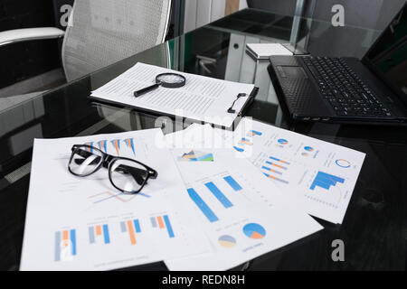Finanzielle Dokumente mit Lupe und Versicherung liegen auf Schwarzen Tisch im Büro close-up Stockfoto