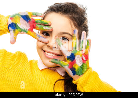 In der Nähe von süßen Schulmädchen in gelb Pullover lächelnd in die Kamera und zeigen Hände in bunten Farben isoliert auf weiss lackiert Stockfoto