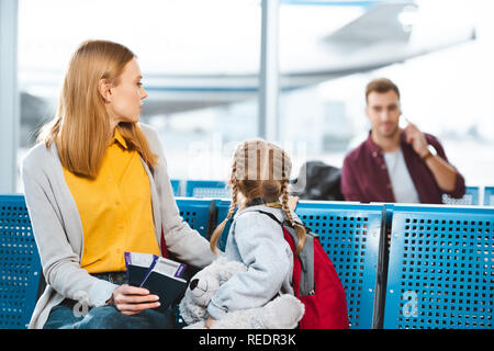 Selektiver Fokus der Mutter holding Pässe mit Flugtickets in der Nähe der Tochter und Mann im Flughafen Stockfoto