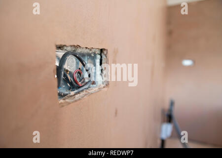 Erste fix inländischen Elektrik in einem frisch Verputzte Wand. Stockfoto