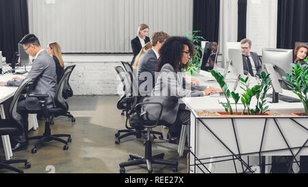 Seitenansicht der professionellen multiethnischen junge Geschäftsleute arbeiten mit digitalen Geräten in Open Space Office Stockfoto