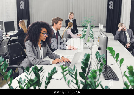 Professionellen multiethnischen junge Geschäftsleute arbeiten mit digitalen Geräten in Open Space Office Stockfoto