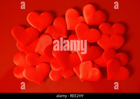 Eine Menge Satin rot Herzen auf eine rote Fläche. St Valentines Tag. Herzlichen Glückwunsch zum Valentines Tag. Liebe und Partnerschaft. Stockfoto