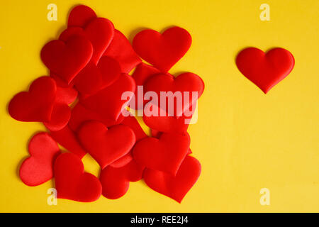 Eine Menge Satin rot Herzen auf einem gelben Oberfläche. St Valentines Tag. Herzlichen Glückwunsch zum Valentines Tag. Liebe und Einsamkeit. Stockfoto