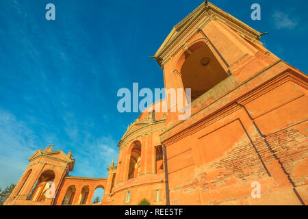 Ansicht von unten der Madonna di San Luca Wallfahrtskirche und Basilika Kirche an einem sonnigen Tag mit blauen Himmel. Kathedrale von San Luca auf den Hügeln von Bologna, Emilia-Romagna, Italien mit Glockenturm. Stockfoto