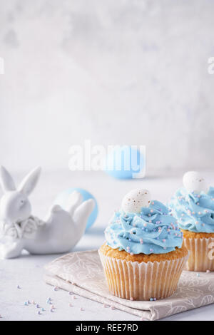 Ostern Vanille Cupcakes mit Cream Cheese frosting und Candy Eier. Cute bunny im Hintergrund. Stockfoto