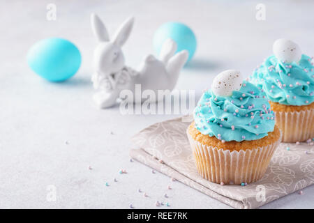 Ostern Vanille Cupcakes mit Cream Cheese frosting und Candy Eier. Cute bunny im Hintergrund. Stockfoto