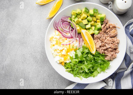 Salat mit Thunfisch, Avocado, Zwiebel, Ei und Zitrone. Frühjahr gesunde köstliches Mittagessen auf hellgrauem Hintergrund Stockfoto