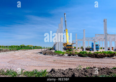 Mobilkran ist die Montage sehr große Betonskelett des gewerblichen Gebäude. Landschaft in städtischen Gebiet mit Maschinen verwandeln, Menschen arbeiten. Anzeigen o Stockfoto