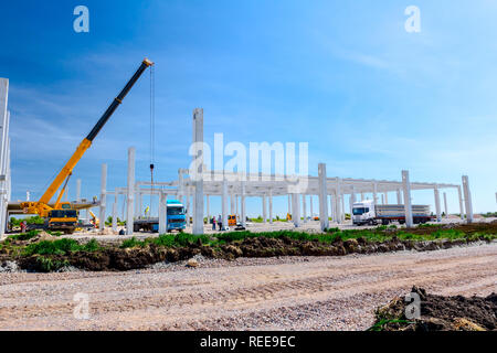 Mobilkran ist die Montage sehr große Betonskelett des gewerblichen Gebäude. Landschaft in städtischen Gebiet mit Maschinen verwandeln, Menschen arbeiten. Anzeigen o Stockfoto