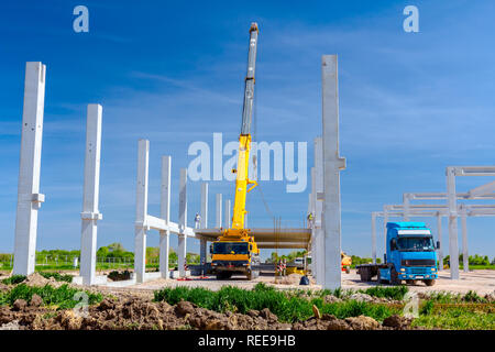 Mobilkran ist die Montage sehr große Betonskelett des gewerblichen Gebäude. Landschaft in städtischen Gebiet mit Maschinen verwandeln, Menschen arbeiten. Anzeigen o Stockfoto