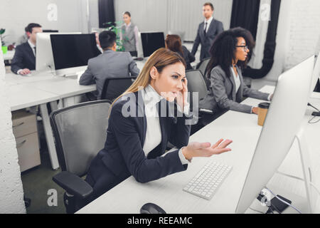 Junge Geschäftsfrau leiden unter Kopfschmerzen, betonte und suchen Sie auf dem Desktop Computer im Büro Stockfoto