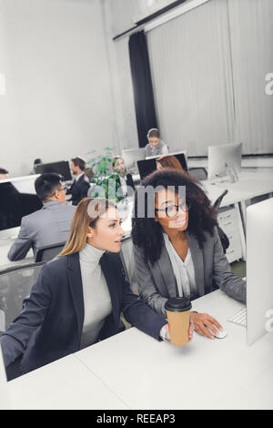 Hohe Betrachtungswinkel von schönen jungen multiethnischen Unternehmerinnen mit dem Desktop Computer gemeinsam im Büro Stockfoto