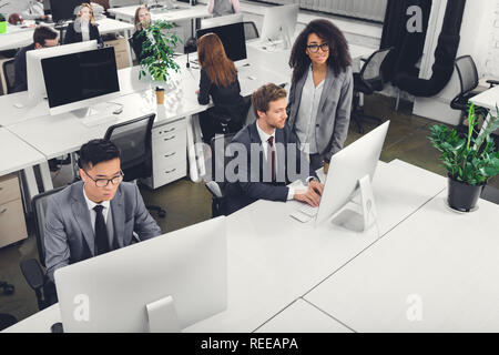Hohe Betrachtungswinkel der multirassischen Geschäftsleute mit dem Desktop Computer im Büro Stockfoto