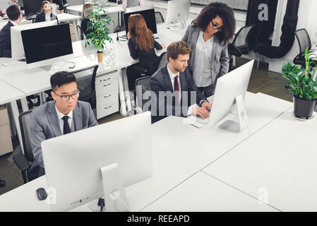 Hohe Betrachtungswinkel und der Multiethnischen Geschäftsleute mit dem Desktop Computer im Büro Stockfoto