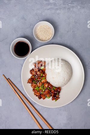 Reis und Hähnchen teriyaki auf eine leichte Platte auf einem grauen Hintergrund. Ansicht von oben Stockfoto