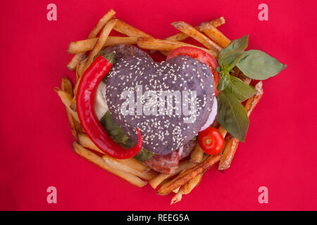 Herzförmige schwarz Hamburger und Pommes Frites, liebe Burger fast food Konzept, Valentinstag Überraschung zum Abendessen, Holz- Hintergrund, Ansicht von oben flach Stockfoto