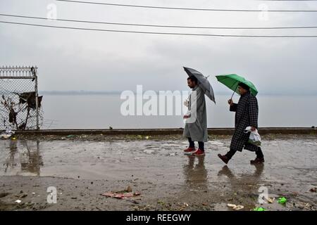 Kaschmir Bewohner halten Regenschirme, wie Sie während der niederschläge in Srinagar, Indien verwalteten Kaschmir gehen. Die obere erreicht am Montag erhielt Schneefall, Regen peitschte Srinagar, und andere Teile des Kaschmir Tal. Das Wetter hat der Mensch mäßiger bis starker Regen und Schneefall über den Zustand während der nächsten 24 Stunden prognostiziert. Stockfoto