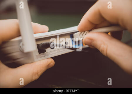 Mann stecken Internet Kabel in WLAN-Router. Stockfoto