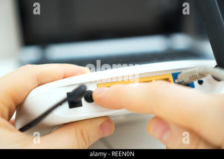 Mann Drücken der Netztaste auf der WLAN-Router. Stockfoto