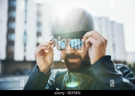 Männliche Fahrradkurier mit Helm aufsetzen Sonnenbrille in der Stadt. Stockfoto