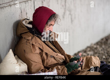 Obdachlose Bettler sitzen draußen in der Stadt bitten um Geld Spende. Stockfoto