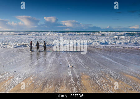 Menschen in Neoprenanzüge stehen an der Küste bei Fistral Beach in Newquay Cornwall. Stockfoto